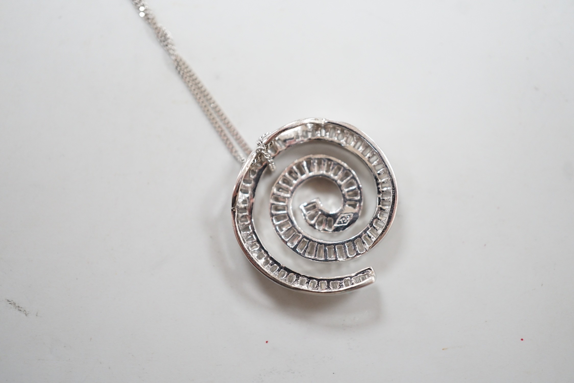 A modern 750 white metal and baguette cut diamond set whorl design pendant, 22mm, gross 4.5 grams, on a 9ct white gold fine link chain, 46cm, 1.1 grams.